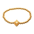 Gold bracelet made of small gold balls with a heart-shaped charm in the center, secured with a spring ring clasp